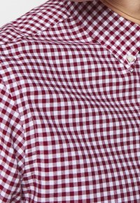 Red and white checked button-up shirt, featuring a classic gingham pattern, lightweight fabric, and a standard collar design.