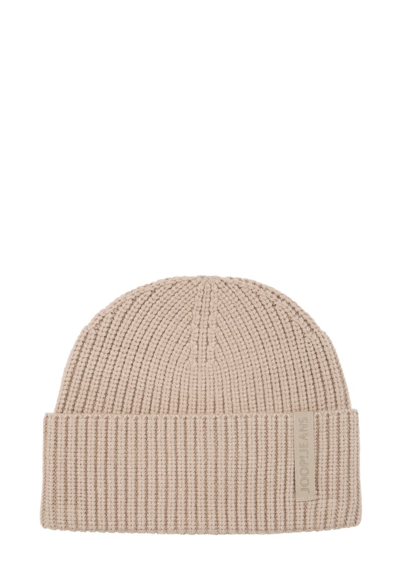 Beige gebreide muts met geribbelde textuur, omgeslagen rand en een klein stoffen label aan de zijkant, die een eenvoudige, functionele stijl uitstraalt.