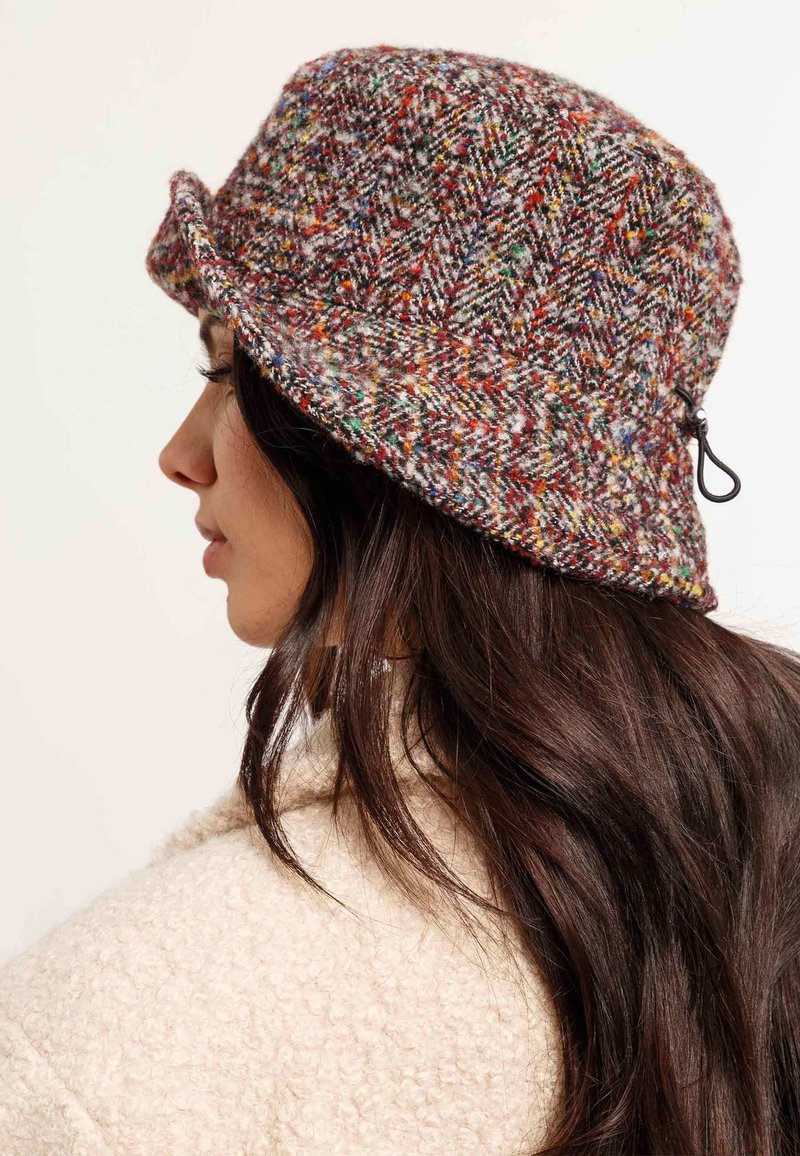 Cappello a secchiello di lana multicolore con motivo a zig-zag, dotato di un bordo flessibile e di un cordino regolabile sul lato.
