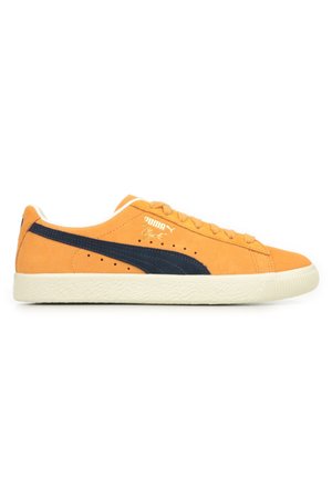 Baskets en daim orange avec une bande bleu marine, dotées d'une semelle en caoutchouc texturé blanc, de lacets ronds et d'un logo Puma doré sur le côté.