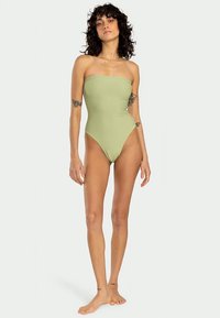 Zeleno enodelno kopalke brez naramnic z gladko teksturo, visoko izrezanimi nogami in minimalnim dizajnom, ki ima strukturiran bust.
