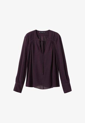 Blusa viola realizzata in tessuto leggero, con scollatura a chiave, maniche lunghe e dettagli arricciati sulle spalle e sui polsini.