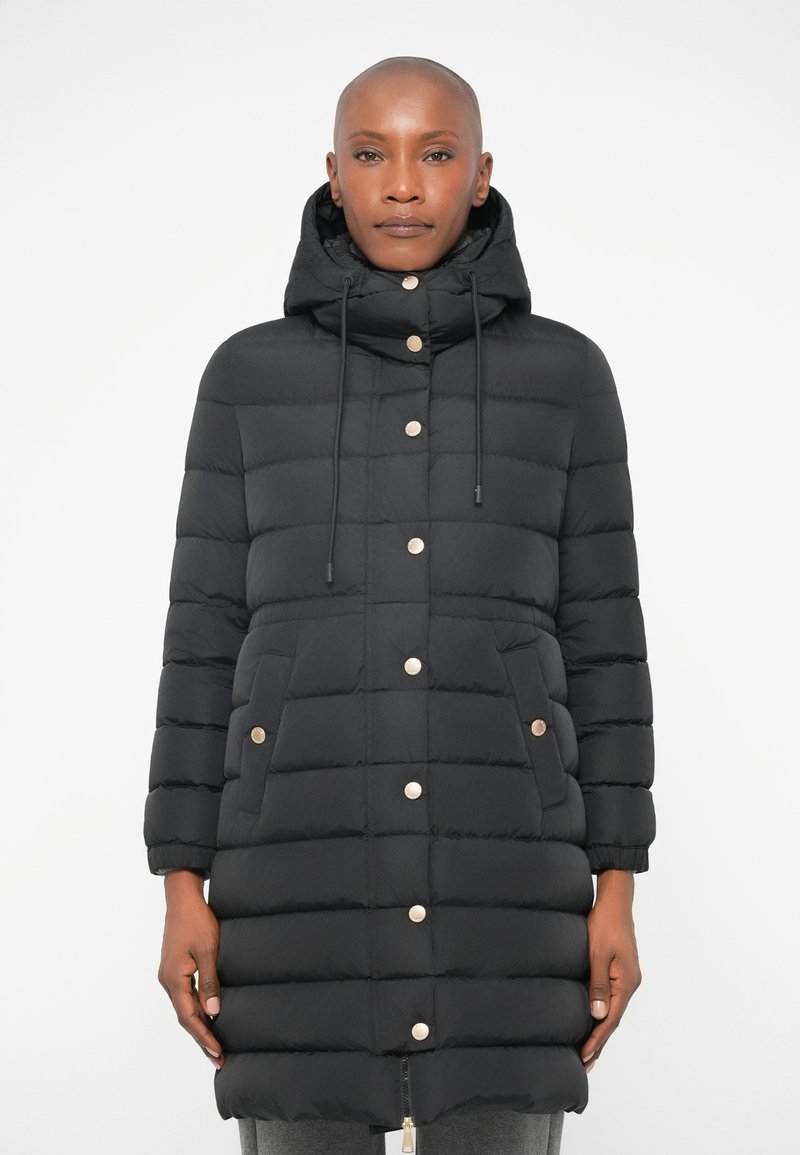 Black puffer coat with a hood, featuring gold-tone snap buttons, two front pockets, and quilted texture. Overall length reaches mid-thigh.