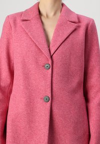 Fuchsia roze wollen blendjas met een gekartelde kraag, dubbele knoopsluiting en een gladde textuur. Tailored fit met strakke lijnen.