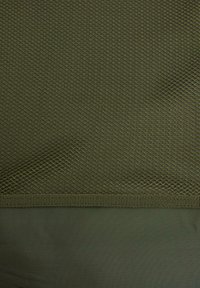 Olīvu zaļš acu audums ar dimanta rakstu augšdaļā, ko apjož zemāk esoša gluda un plakana daļa tumšākā zaļā krāsā.