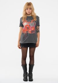 Graphic gray t-shirt with red and black splattered design. Paired with a dark denim skirt and black knee-high, buckle-embellished boots.