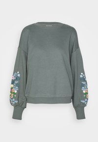 Sweatshirt vert à coupe décontractée, avec des poignets côtelés et des broderies florales aux couleurs comprenant du bleu, du rose et du jaune sur les manches.