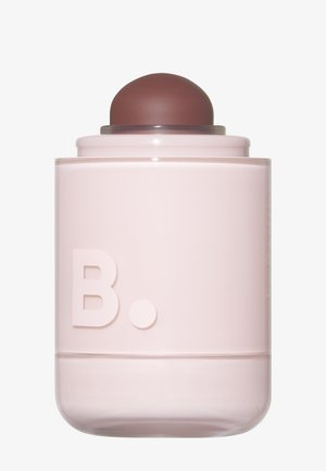 Brauner Balm-Applikator mit rundem Kopf auf einem hellrosa zylindrischen Behälter mit geprägtem Buchstaben B und Punkt auf der Vorderseite.