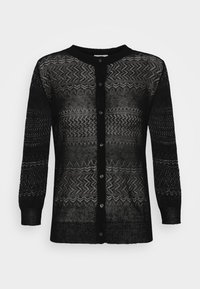 Svart kappa med ett stickat mönster som innehåller zigzag- och geometriska mönster. Långa ärmar och knappar framtill kompletterar den lätta, genomskinliga texturen.