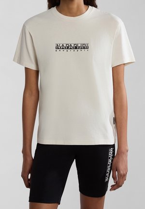 T-shirt en coton crème avec des manches courtes, ornée d'un design de logo graphique noir sur le devant. Associée à un short noir affichant un accent de logo.