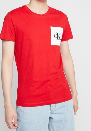 Rotes Baumwoll-T-Shirt mit Rundhalsausschnitt, kurzen Ärmeln und einer weißen Brusttasche mit schwarzem "CK"-Logo. Glatter Stoff, lässiges Design.