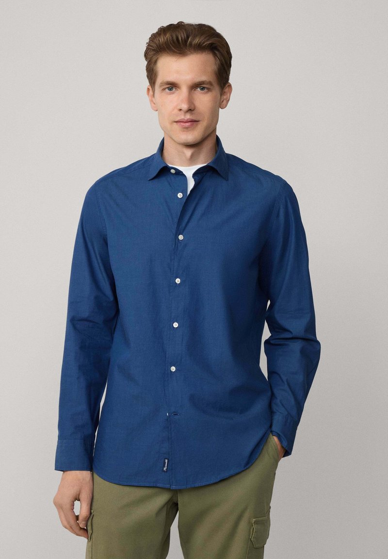 Camisa de botones azul marino en tejido ligero, con cuello puntiagudo, mangas largas y botones blancos. Textura suave con un ajuste casual.