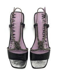 Sandalias de cuero negro con un acabado texturizado, punteras cuadradas y una correa decorativa anudada. Plantillas moradas con detalles de marca.