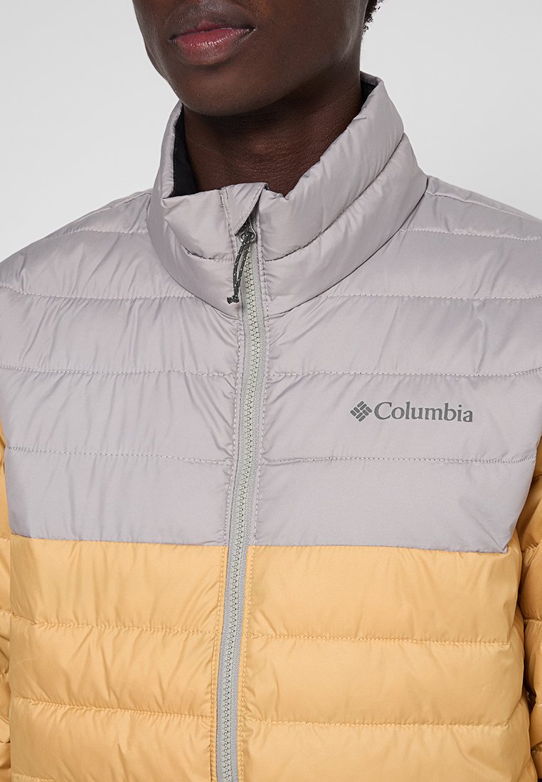 Kurtka puchowa w odcieniach szaro-żółtych. Posiada wysoki kołnierz, poziome pikowanie oraz zamek błyskawiczny z przodu. Logo umieszczone na klatce piersiowej.
