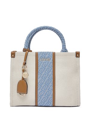 Sac à main en tissu beige avec un panneau central à motifs bleus et une anse, des accents en cuir marron, et un porte-bonheur de marque rond en métal doré.