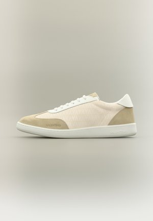 Baskets basses beige et blanches Valentino avec accents en daim, lacets et nom de marque embossé sur le côté et la semelle.