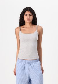 Grey fitted tank top with thin straps, made of soft fabric. Worn with light blue and white striped pajama pants.