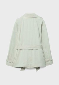 Jasnobeżowy trencz widziany od tyłu, z paskiem w talii i mankietami zapinanymi na guziki, pokazany na jednolitym tle.