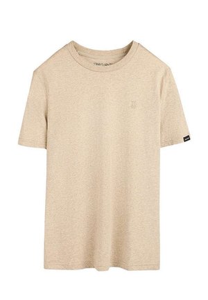 T-shirt beige à manches courtes et col rond, avec un logo de marque discret sur la poitrine et une petite étiquette noire sur la manche gauche.