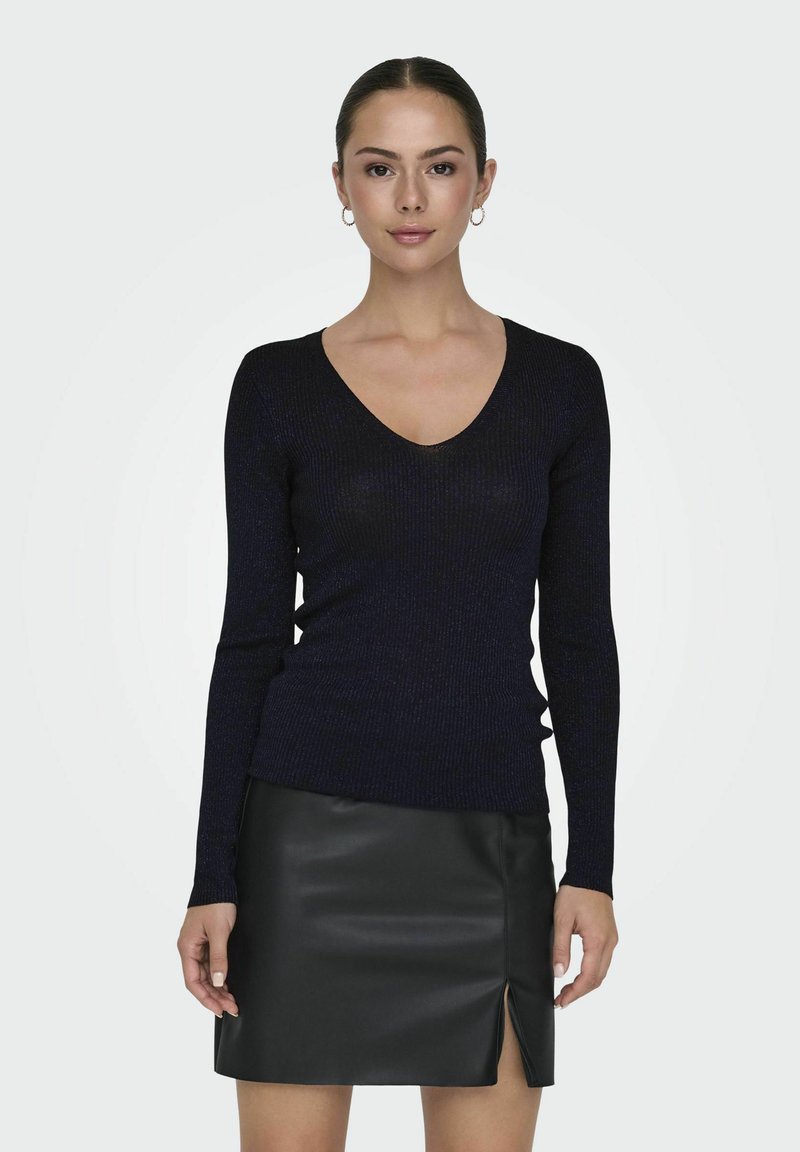 Marineblaue, gerippte V-Ausschnitt-Pullover mit langen Ärmeln, kombiniert mit einem figurbetonten, schwarzen Leder-Minirock mit Schlitzdetails an der Vorderseite.