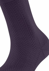 Chaussette violet foncé dotée d'un motif en chevrons, fabriquée en tissu texturé avec une finition lisse et un ajustement serré autour de la cheville.