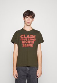 Oliven grøn cotton t-shirt med rød grafisk tekst "CLAIM YOUR DENIM RIGHTS BLEND" på forsiden. Korte ærmer, rund hals design.