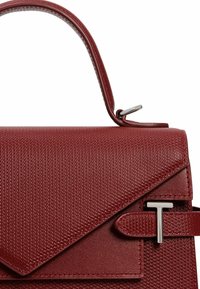 Bolso de mano texturizado en rojo con una forma estructurada, que cuenta con una solapa triangular, herrajes plateados y un asa corta.
