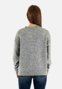 Suéter de punto gris con un diseño holgado, dobladillo y puños acanalados, y una textura suave. La vista trasera presenta un cuello redondeado.