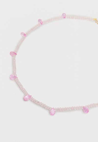 Collier avec de petites perles rondes rose pâle et de plus grandes perles en forme de goutte rose facettées, espacées uniformément le long du fil sur fond blanc.