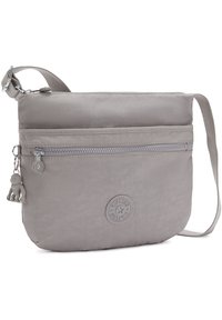 Borsa a tracolla in tessuto grigio con una tasca frontale con zip, un patch rotondo con logo e un piccolo charm coordinato attaccato alla zipper. Tracolla regolabile.