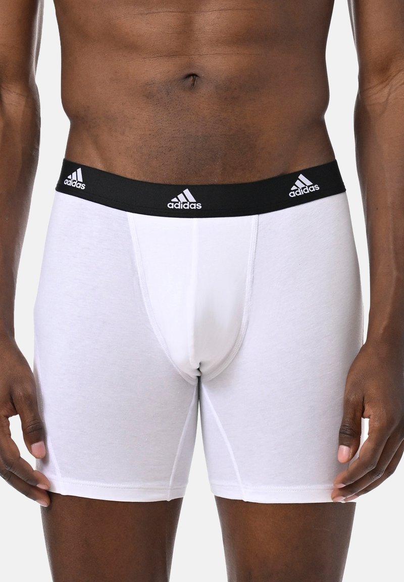 Białe bawełniane bokserki z czarnym elastycznym paskiem, na którym znajdują się trzy białe logo Adidas. Dopasowany krój o gładkiej teksturze.
