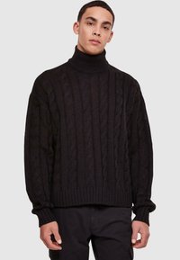 Maglione a collo alto nero in maglia spessa con motivo a treccia, polsini e orlo a coste; vestibilità ampia, texture spessa e design informale.