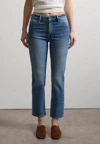 Blaue Denim-Jeans mit hoher Taille, geradem Bein, leichter Auswaschung und vier Taschen. Abgeschlossen mit einer mittelblauen Wäsche und Standardnähte.