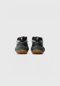 Black and gray hiking shoes with a textured leather and mesh upper, Vibram outsole, and unique heel design featuring a yellow accent.