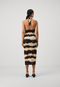 Crna i smeđa tie-dye midi haljina s halter dekolteom, koja ima nisku pozadinu i uski siluet, izrađena od laganog materijala.
