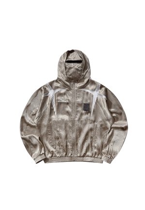 Giacca a vento con cappuccio color beige chiaro Umbro con accenti bianchi, cerniera frontale, polsini elastici e piccolo logo a toppa sul petto.