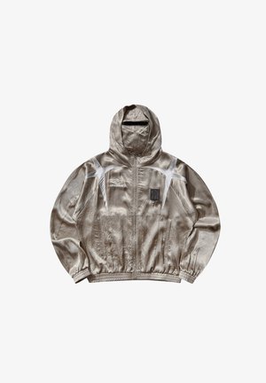 Giacca a vento con cappuccio color beige chiaro Umbro con accenti bianchi, cerniera frontale, polsini elastici e piccolo logo a toppa sul petto.