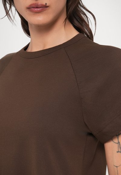 Καφέ βαμβακερό μπλουζάκι με στρογγυλή λαιμόκοψη, κοντά raglan μανίκια, λεία υφή και στενή γραμμή.