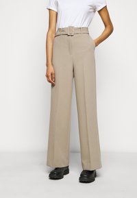 Pantalons taille haute beiges en tissu lisse, avec une coupe large, des passants de ceinture et une ceinture assortie avec une boucle rectangulaire.