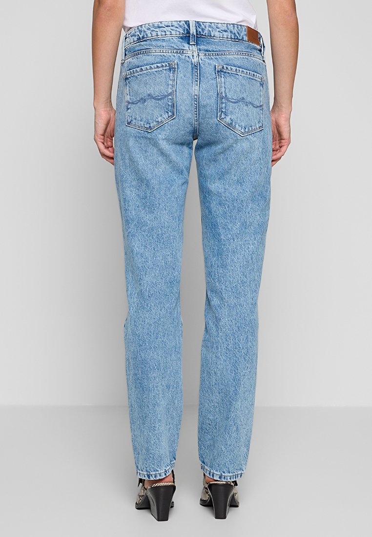 Jean en denim bleu clair avec une coupe droite, dotés de poches arrière et d'une patte en cuir sur la taille. Texture légèrement délavée.