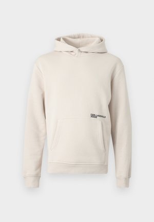 Világos bézs színű kapucnis pulóver, puha anyagból készült, elülső zsebbel és egy kis fekete logóval az alsó bal oldalon.