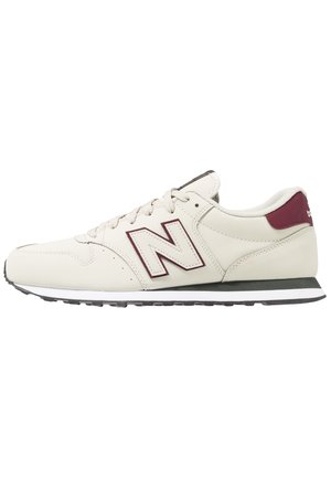 Hvid og mørkerød New Balance sneaker med snørebånd, polstret sål og logo på siden, vist fra den ydre side.
