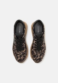 Paire de baskets à imprimé léopard avec des lacets noirs et des semelles couleur fauve, vues de dessus sur fond blanc.