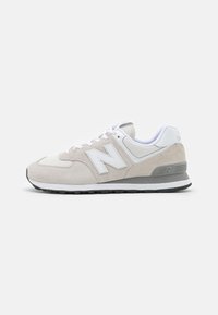 Baskets New Balance avec un dessus en suède gris clair, des accents en maille blanche et une semelle en caoutchouc grise avec des détails texturés et un logo.