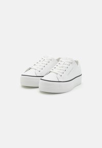 Fehér fűzős sportcipő, gumitalppal, textúrált felülettel és fekete csíkkal az élén. Oldalán logóval és lekerekített orr designnal rendelkezik.