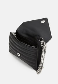 Czarna pikowana skórzana torebka z srebrnym zapięciem na zatrzask i łańcuszkowym paskiem. Posiada wiele przegrody i gładką fakturę.