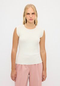 Hladký, bezrukávový top v off-white barvě s kulatým výstřihem. Má přiléhavý střih a jemnou texturu, doplněný o růžové široké kalhoty.