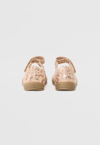 Vedere din spate a sandalelor roz, cu un model floral și un finisaj lucios, curele ajustabile pentru glezne și talpă din cauciuc.