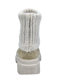 Bota de ante beige con un eje de punto ligero gris claro, doblado y acanalado. Suela gruesa beige con detalles de tracción. Vista trasera que muestra las texturas del material.