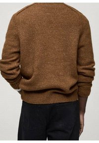 Ruskea neulepaita, jossa on ribbikuvioidut hihansuut ja helma, sekä teksturoitu pinta ja raglan-hihat. Yhdistetty mustiin housuihin.